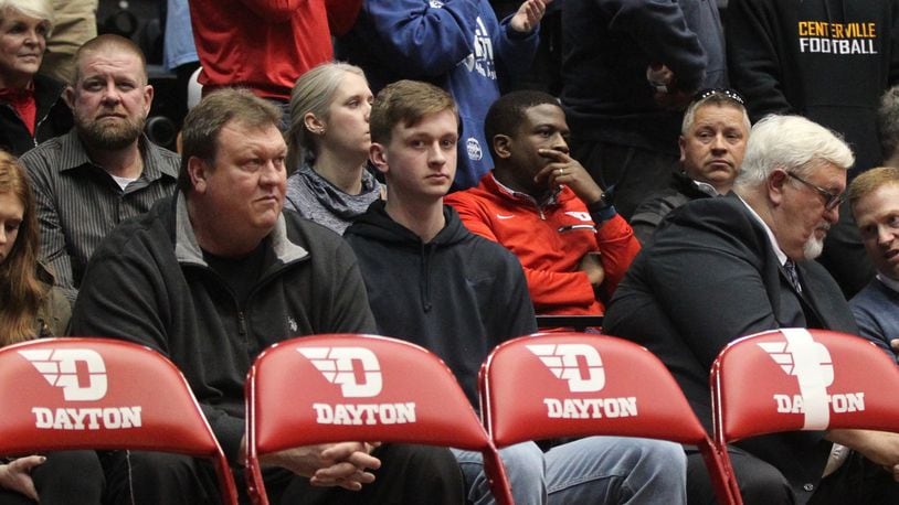 Zach Benton, center, sits behind the Dayton bench during a game against Massachusetts on Sunday, Jan. 13, 2019, at UD Arena.