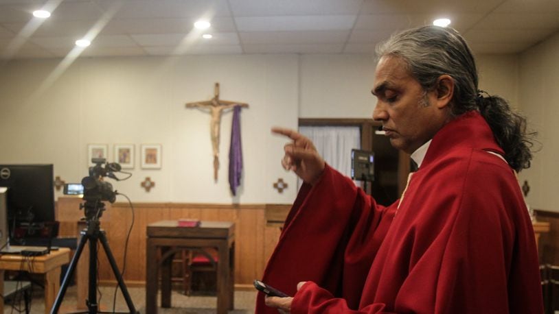 Father Satish Joseph directs his crew before livestreaming a service on Good Friday afternoon. JIM NOELKER/STAFF