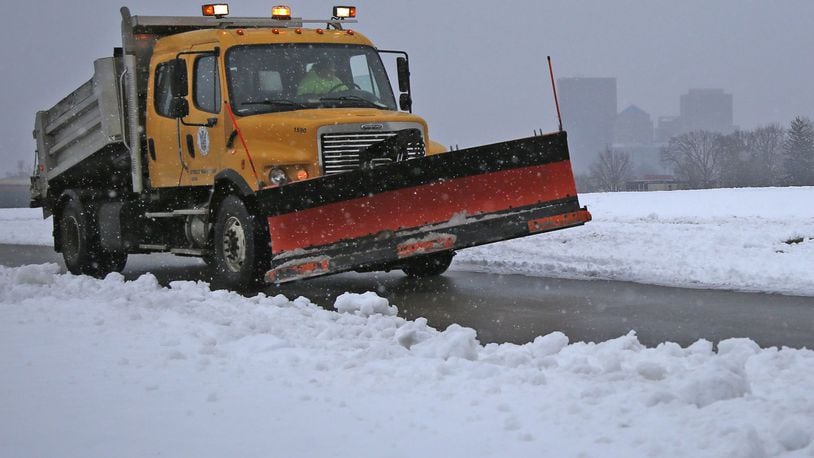 Snow obscures the Dayton skyline as a snow plow driver checks road conditions on North Bend Boulevard along the Great Miami River on Thursday. TY GREENLEES / STAFF