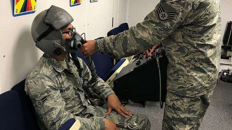 Staff Sgt. Luciano Cattaneo, an Aerospace and Operational technician and NCO in charge of Administration/Scheduling at the United States Air Force School of Aerospace Medicine, helps a student get fitted for an oxygen mask in the hyperbaric chamber. (Courtesy photo)