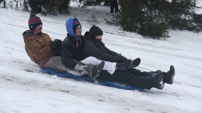 A group of adults join in the fun as they take a turn sledding down a snow covered hill on the Wittenberg University campus Sunday. BILL LACKEY/STAFF