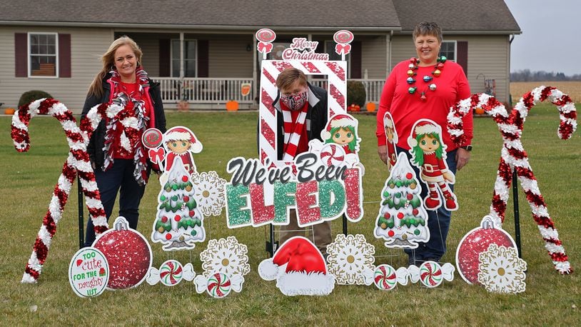 Robyn Fell, left, and her son, Zan, with Kim Harris in a front yard that has been "Elfed" Tuesday. BILL LACKEY/STAFF
