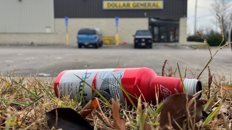 An empty beer bottle in a grassy area outside of a Dollar General's parking lot in Dayton. CORNELIUS FROLIK / STAFF