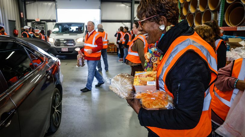 State Farm volunteer Linda Nervis, along with 25 other volunteers, helps load vehicles with food at the Dayton Foodbank Thursday morning, Nov. 17, 2022. JIM NOELKER/STAFF