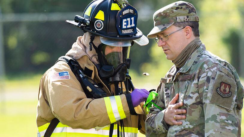 Paramedic Jared Spaeth of the 788th Civil Engineer Squadron Fire Department ties a ribbon around an Airman’s arm to mark his level of ‘wounds’ during a ‘fuel spill’ exercise May 19 at Wright-Patterson Air Force Base. Readiness exercises are routinely held to streamline unit cohesion when responding to emergencies. U.S. AIR FORCE PHOTO/WESLEY FARNSWORTH