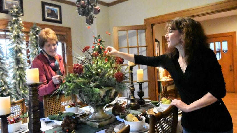 Diana Begley and Sonya Lyons work with pieces selected for decorating the dining room table of Lyons home for the annual Christmas in the Village Home Tour. CONTRIBUTED