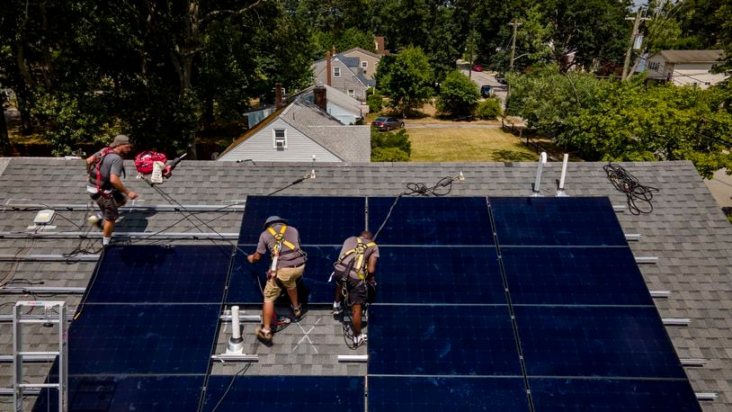 The city of Springboro amended its planning and zoning code to make it easier for residents and businesses to install solar panels on their homes and structure. This file photo shows a company installing an array of solar panels on a roof in Massapequa, N.Y. last month. (AP Photo/John Minchillo)
