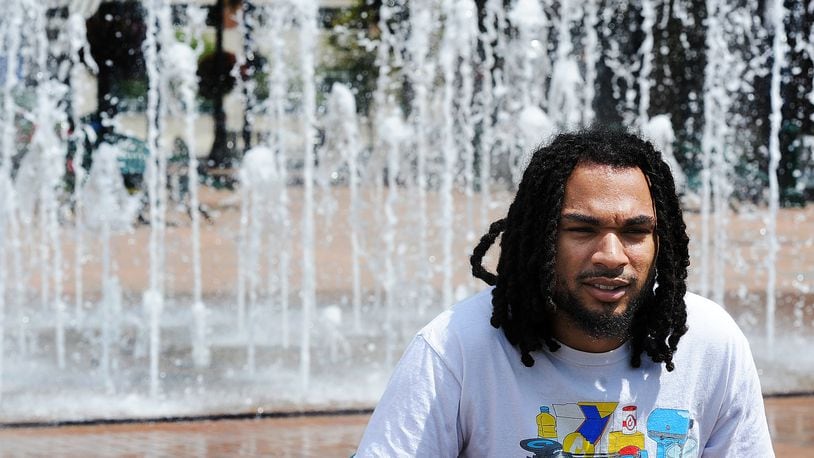 Jeremiah Peters, 23, talks about the importance of governments communicating about water quality with their citizens while sitting in front of the interactive fountain at Riverscape MetroPark in Dayton on Wednesday, Aug. 16, 2023.  MARSHALL GORBY\STAFF