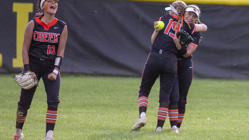 Beavercreek's Alyssa Lewis (18) shouts to her teammates while center fielder Kate Schell (19) hugs right fielder Ashley Norris after Norris ran down a hard-hit line drive for the final out of the Beavers' 5-4 victory over Western Brown in a Division I region semifinal at Centerville High School. Jeff Gilbert/CONTRIBUTED