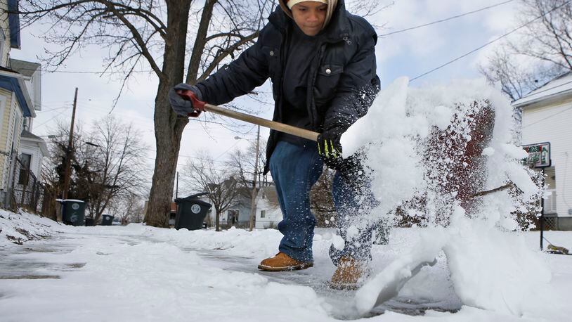 Corey Williams shovels the sidewalk in front of his home on E. Second St. in Dayton. TY GREENLEES / STAFF