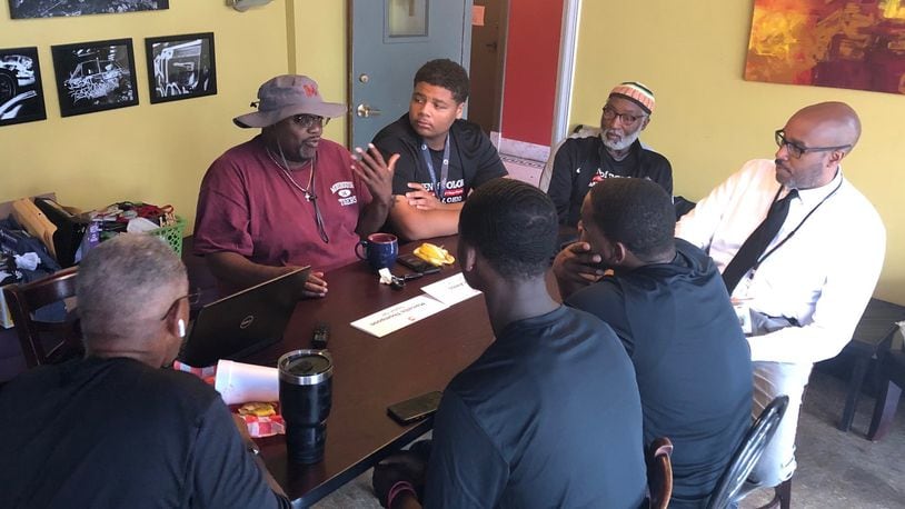Dayton Public Schools Males of Color coordinator John Rogers (in white shirt) and facilitator Joshua Nalls (hand on chin) discuss possible program improvements with students and community leaders in August 2019. JEREMY P. KELLEY / STAFF