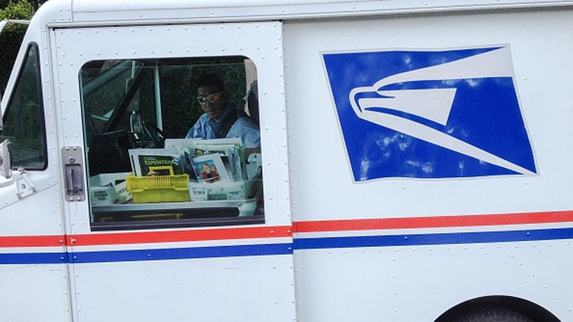 Santa Monica, Ca - October 17, 2014. A U. S. mailman tends to a bin of mail aboard his mail truck .