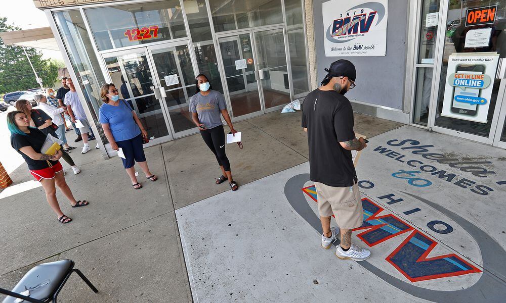 Dozens of people wait in line outside the Ohio Bureau of Motor Vehicles in the Southern Village Shopping Center in Springfield earlier this year after locations were reopened across the state. BILL LACKEY/STAFF