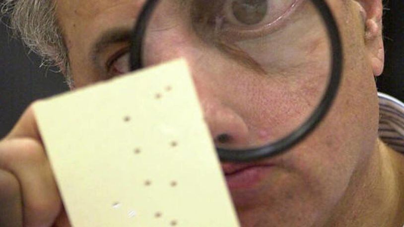 Hanging chads are not new to South Florida. In this 2000 photo, Broward Countycanvassing board member Judge Robert Rosenberg used a magnifying glass to examine a disputed ballot.