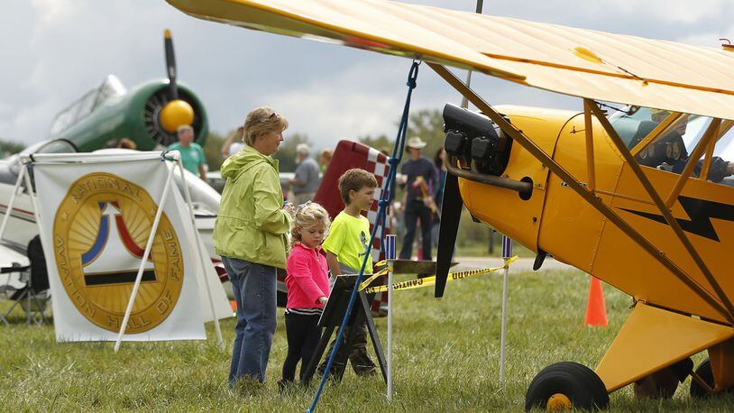 In this 2015 file photo, Brother and sister Mallory and Jack Behm, from Springboro, look at airplanes with their grandmother, Marilyn Bohardt, at the Great Wright Brothers Aero Carnival on Huffman Prairie. The event was hosted by the Dayton Aviation Heritage National Historical Park and included aircraft from the 1930’s including North American T-6, left, and the Piper Cub at right. Other period activities included a sheep-herding demonstration and propeller shaping by hand. TY GREENLEES / STAFF FILE PHOTO