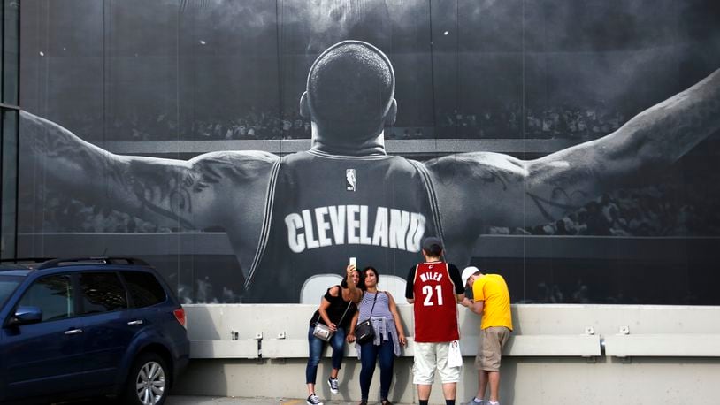 Cleveland Cavalier fans Teig Colgrove, left, and Sayeh Ashley, center, of Akron, take a selfie in front of a mural of Cleveland Cavaliers' LeBron James outside the Quicken Loans Arena early Wednesday, June 22, 2016 while waiting for a parade celebrating the Cleveland Cavaliers' NBA Championship through downtown Cleveland. (AP Photo/Gene J. Puskar)