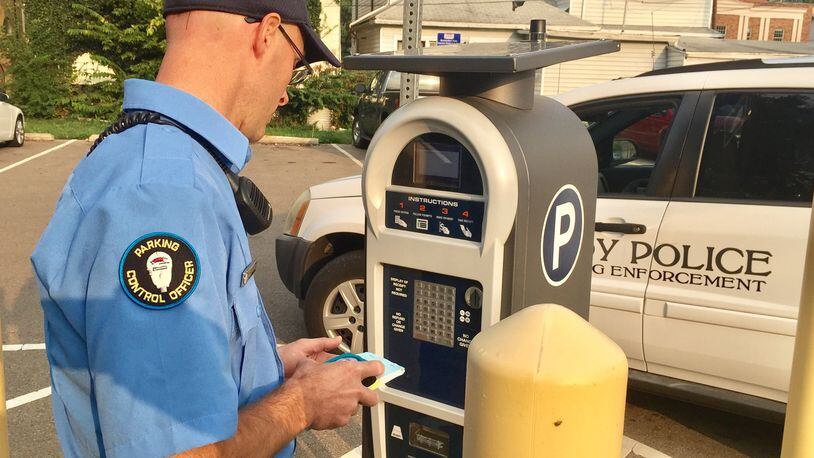 Dan Griffieth, Troy parking control officer, checks on a parking kiosk in the South Cherry Street parking lot downtown. STEVE BAKER/CONTRIBUTED