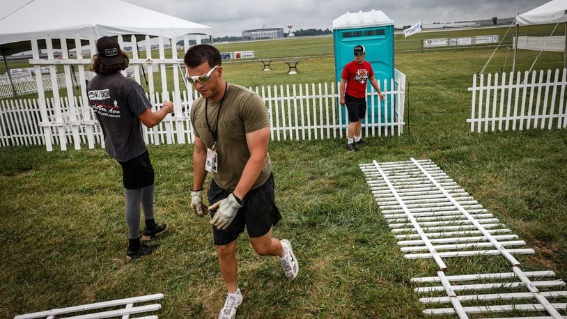 Dayton Air Show workers from left, Connor Buchanan, Nick Hoff and Austin Lackey setup a fence in the private section of the Dayton Air Show in preparation of this weekends show. JIM NOELKER/STAFF