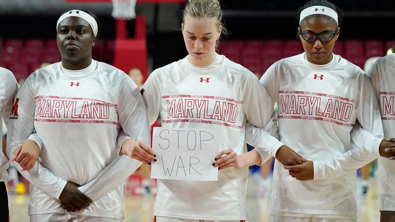 Maryland guard Taisiya Kozlova, center, holds a sign reading "No War" while standing with guard Ashley Owusu, left, and guard Shyanne Sellers, right, prior to a college basketball game against Florida Gulf Coast in the second round of the NCAA tournament, Sunday, March 20, 2022, in College Park, Md. (AP Photo/Julio Cortez)