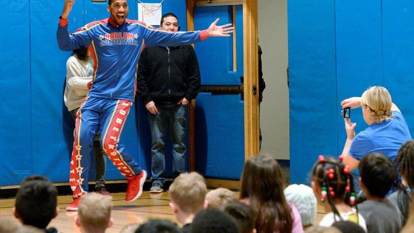 Harlem Globetrotter Zeus McClurkin places a spinning basketball on the finger of 9-year-old Chayna Griffith inside the Prairies Childhood Development Center at Wright-Patterson Air Force Base Dec. 13. McClurkin reviewed the history of the Globetrotters and reminded the students about the importance of teamwork and respecting each other before inviting some of them to participate in basketball tricks. (U.S. Air Force photo/Ty Greenlees)