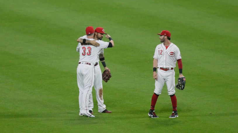 Jesse Winker, left, gets a hug from Nick Castellanos as the Reds celebrate a victory against the Brewers on Friday, May 21, 2021, at Great American Ball Park in Cincinnati. David Jablonski/Staff