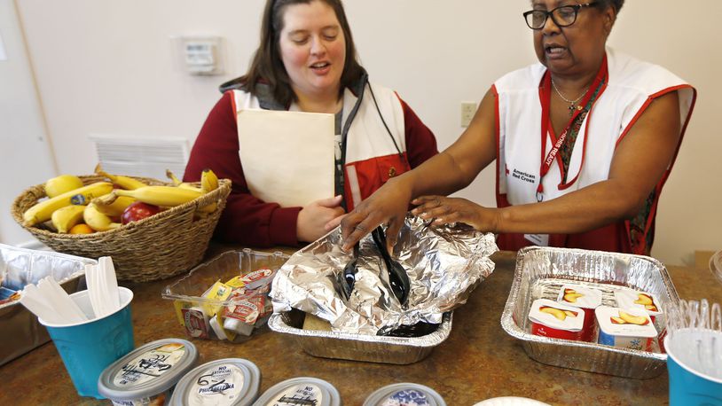 Red Cross Live Safety Asset Protection specialist Danielle Carsner, left, and volunteer Warkoneta Tucker with breakfast offering for shelter clients at Bethesda Temple at Salem Avenue, 3701 Salem Avenue, on June 14. The Red Cross consolidated its shelters to this one location. TY GREENLEES / STAFF