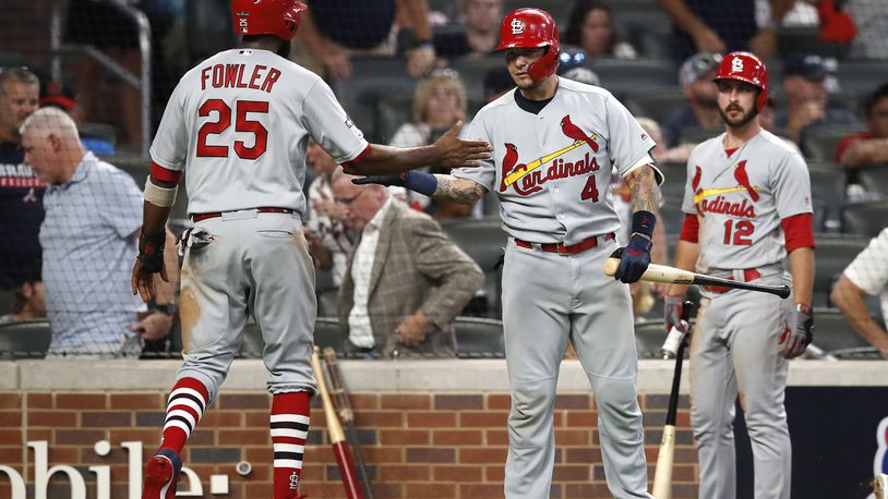 ATLANTA, GEORGIA - OCTOBER 03:  Dexter Fowler #25 of the St. Louis Cardinals is congratulated by his teammate Yadier Molina #4 after scoring a run against the Atlanta Braves during the ninth inning in game one of the National League Division Series at SunTrust Park on October 03, 2019 in Atlanta, Georgia. (Photo by Todd Kirkland/Getty Images)