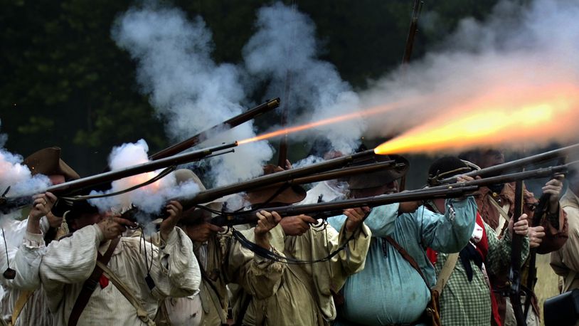 Fire explodes from a row of militia muskets as the militiamen in the 225th anniversary re-enactment of the Battle of Peckuwe take aim at the Native American warriors Sunday, July 17, 2005, at George Rogers Clark Park in Springfield. The re-enactment commemorates the largest Revolutionary War battle fought west of the Allegheny Mountains which took place on the site of the current state park. Staff photo by Bill Lackey