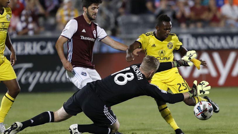 Columbus Crew defender Harrison Afful, back right, has his shot blocked by Colorado Rapids goalkeeper Zac MacMath, front, as defender Eric Miller looks on in the second half of an MLS soccer game Saturday, June 3, 2017, in Commerce City, Colo. The Rapids won 2-1. (AP Photo/David Zalubowski)