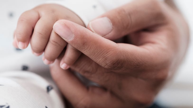Parent holding baby's hand (stock photo).