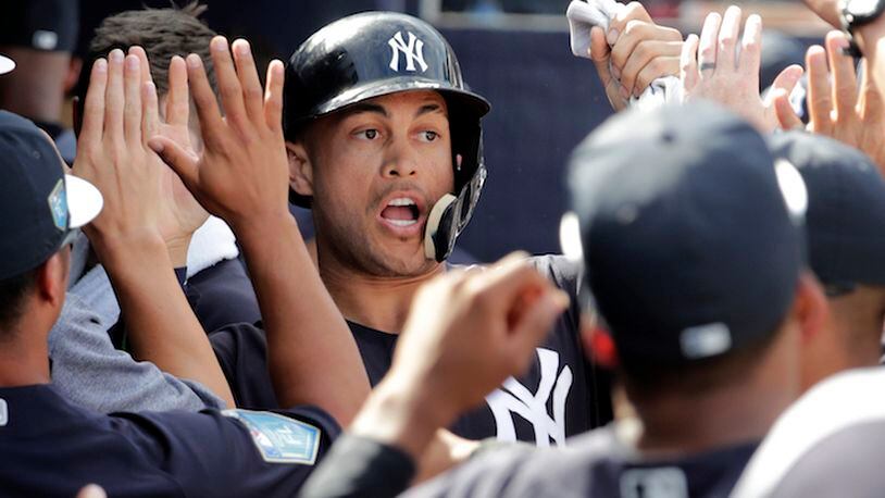 New York Yankees' Giancarlo Stanton is congratulated in the dugout after scoring on an RBI single by Didi Gregorius during the fifth inning of a baseball spring exhibition game against the Atlanta Braves, Friday, March 2, 2018, in Tampa, Fla. (AP Photo/Lynne Sladky)
