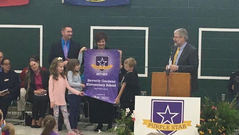 Students at Beverly Gardens Elementary unfurl a new banner recognizing them as a Purple Star military-friendly school, while state schools superintendent Paolo DeMaria (right) speaks to students. JEREMY P. KELLEY / STAFF