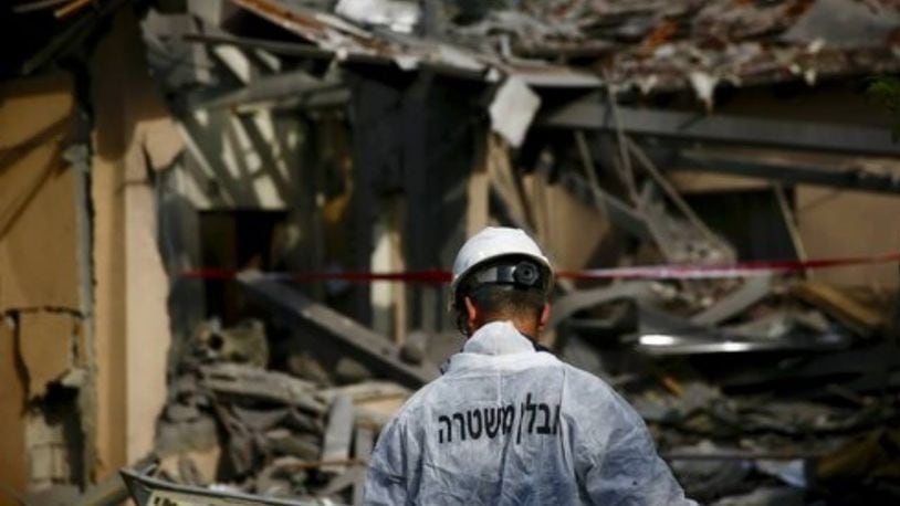 An Israeli police officer inspects the damage to a house hit by a rocket in Mishmeret on Monday.