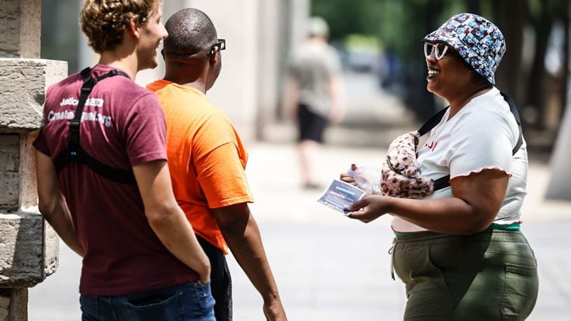 Jasmine Like (right from Dayton) talks with a representative (left) from Created Equal, a national anti-abortion organization that was in downtown Dayton with large signs on Wednesday July 19, 2023. Marcus Bedinger is the person in the middle. JIM NOELKER/STAFF.