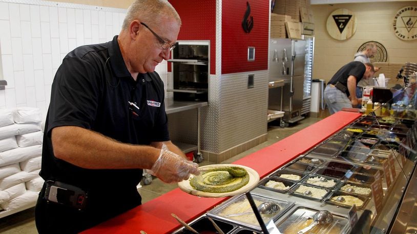 Ray Wiley creates a pizza at his recently opened restaurant Rapid Fired Pizza in Washington Twp. Customers order custom made pizza in a serving line similiar to Chipotle in the new “fast-casual” chain.