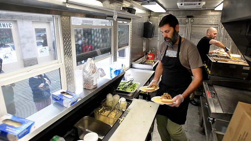 Will Bigham, owner of The Improper Pig, works with Darius Amidi as they serve lunch in The Oinker, the restaurant's food truck, at the Salvation Army's Center of Hope in Charlotte, N.C., on March 14, 2017. (David T. Foster III/Charlotte Observer/TNS)
