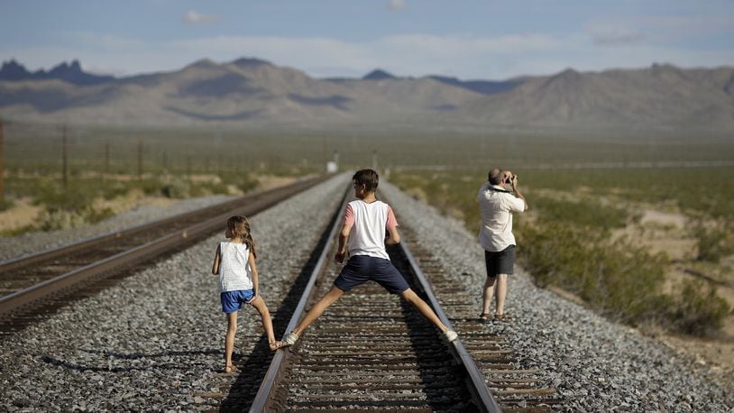A family walks along train tracks, Thursday, Aug. 3, 2017, in Nipton, Calif. One of the nation's largest cannabis companies announced it has bought the entire 80 acre California desert town of Nipton. (AP Photo/John Locher)