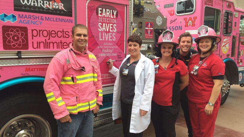 ER physician Dr. Carrie Baker (center) signs the Huber Heights pink fire truck that recently visited Sycamore Medical Center in Miamisburg in support of Breast Cancer Awareness Month and the Pink Ribbon Girls. She’s joined by Chris Warrick of the Huber Heights Fire Department; Michelle Smithson, registered nurse; Todd Geglein, registered nurse; and Kendra Johnson, registered nurse, of Sycamore Medical Center’s Emergency Department. CONTRIBUTED