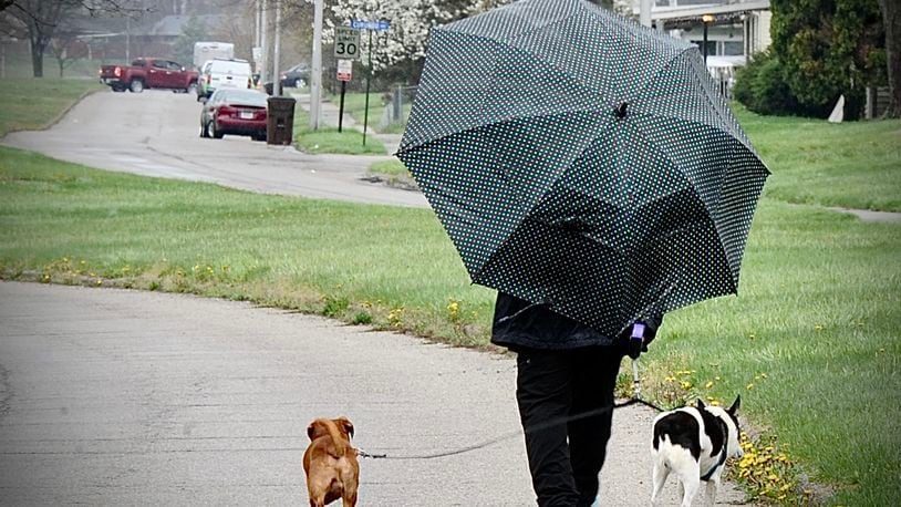 FILE PHOTO: You can expect a lot of dog gone rain Wednesday April 13, 2022. Keep your umbrella handy like this lady in Trotwood walking her dogs on Brumbaugh Boulevard. MARSHALL GORBY \STAFF