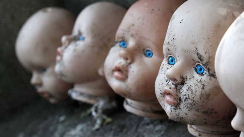 Several children head doll with blue eyes lie in the old yard - scary stories - fear - a fairy tale. Photo: Shutterstock