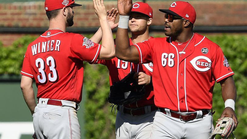 CHICAGO, ILLINOIS - MAY 26: Nick Senzel #15, Yasiel Puig #66, and Jesse Winker #33 of the Cincinnati Reds celebrate the 10-2 win against the Chicago Cubs at Wrigley Field on May 26, 2019 in Chicago, Illinois. (Photo by Quinn Harris/Getty Images)
