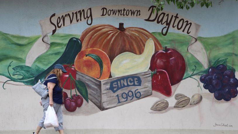 A woman walks by the mural outside Stop-N-Save Foods after shopping inside the West Third Street store. CORNELIUS FROLIK / STAFF