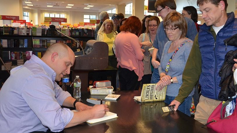 Air Force Research Laboratory engineer, Air Force reservist and author TJ Turner signs copies of his first book, ‘Lincoln’s Bodyguard,’ in April 2015. For his most recent novel, ‘Angel in the Fog,’ he drew inspiration from female colleagues within the laboratory and in military service as well as real-life historical figures. (U.S. Air Force photo/Lori Hughes)