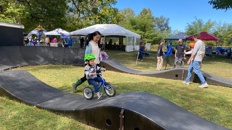 Three-year-old Theodore Chima tries biking on a track during the Wagner Subaru Outdoor Event while his mom, Mengwan Chima, helps him on Saturday, Oct. 1 at Eastwood MetroPark. Eileen McClory / Staff