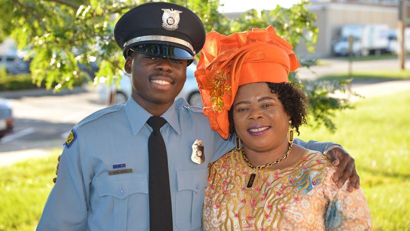 Newly graduated Dayton Police officer Bibebibyo “Bibe” Seko and his mom Sela (orange head wrap) surrounded by their family at Bibe’s graduation. (Photo by Gary Laughlin)