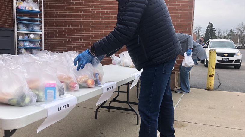 Kettering City Schools employees give out school lunch packages to families in a drive-up service at Fairmont High School on March 24, 2020. JEREMY P. KELLEY / STAFF