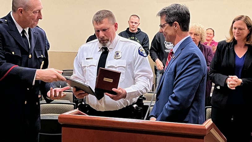 Springboro police Chief Dan Bentley, left, presents the citation to Officer Heath Martin as he was presented the Carnegie Medal for Heroism Thursday, April 4, 2024, during the Springboro City Council meeting. At right is Eric P. Zahren, president and secretary for the Carnegie Hero Fund Commission, who presented the medal. Martin was recognized for his heroism in going into a burning house twice to rescue a disabled man on June 23, 2023. ED RICHTER/STAFF
