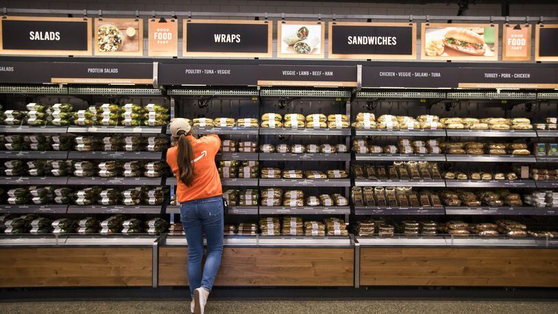 An employee in bright orange restocks the shelves at Amazon Go, the cashier-free prototype store in Seattle at 7th Avenue and Blanchard by the Amazon Spheres, Tuesday Jan. 16, 2018. (Bettina Hansen/Seattle Times/TNS)