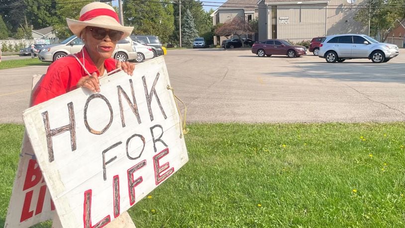 Vivian Skovgard holds up a "Honk for Life" sign outside Women's Med Center Friday morning. The clinic saw a surge of patients following a ruling from a Hamilton County judge temporarily pausing Ohio's Heartbeat law./ STAFF PARKER PERRy