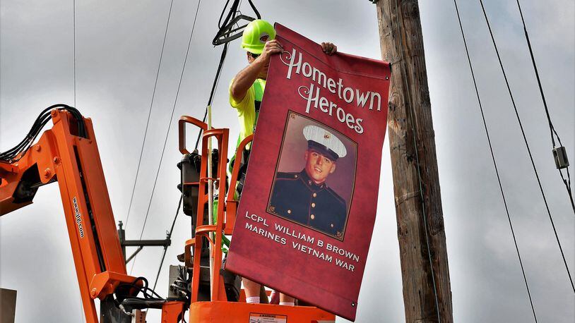 Workers place one of the nearly 200 Hometown Heroes banners saluting men and women from Union Twp., Miami County, for their military service. CONTRIBUTED.